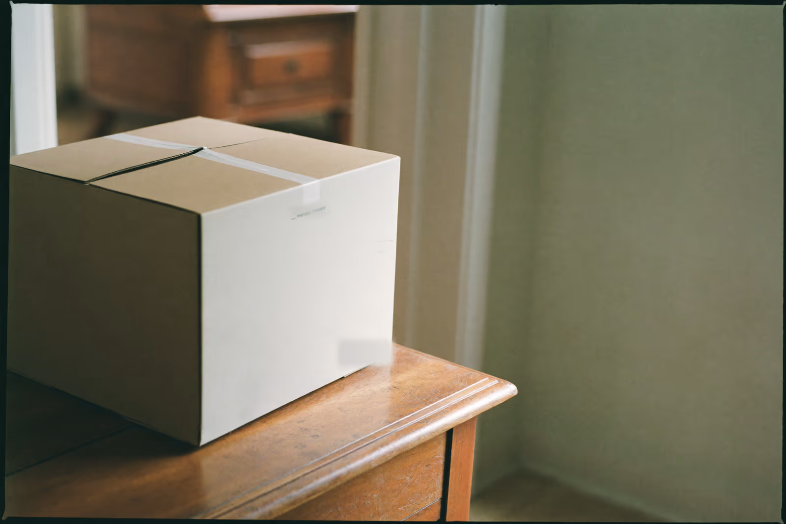 A plain parcel resting on a wooden entryway console